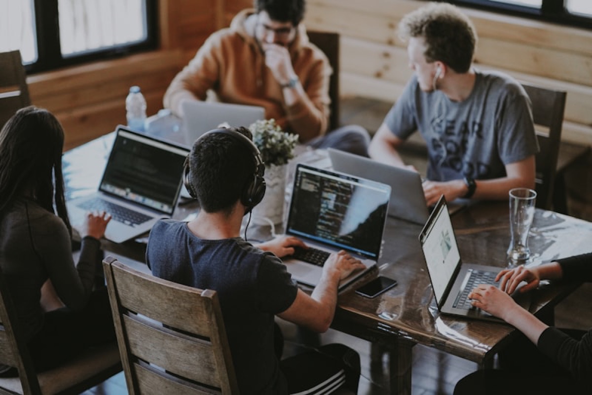 Small team working together at a shared table with laptops